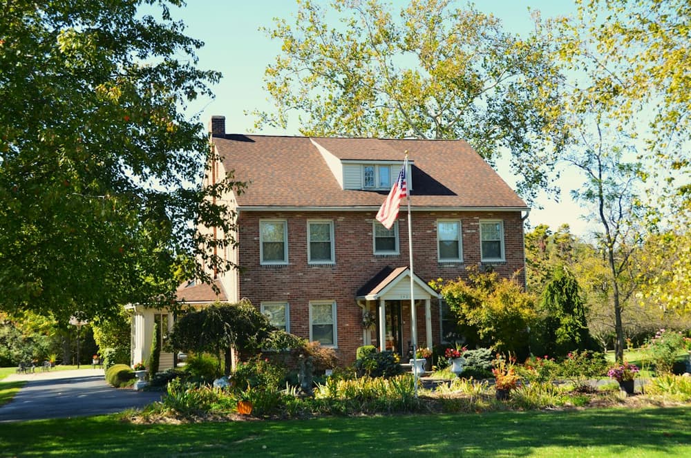 Brick house in fall with a cleared lawn and tidy beds